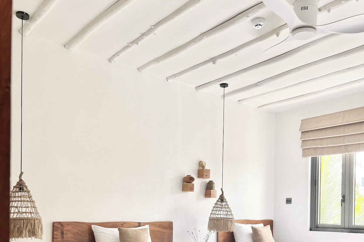 Une chambre avec un lit en bois, un ventilateur de plafond et une fenêtre donnant sur un beau paysage.