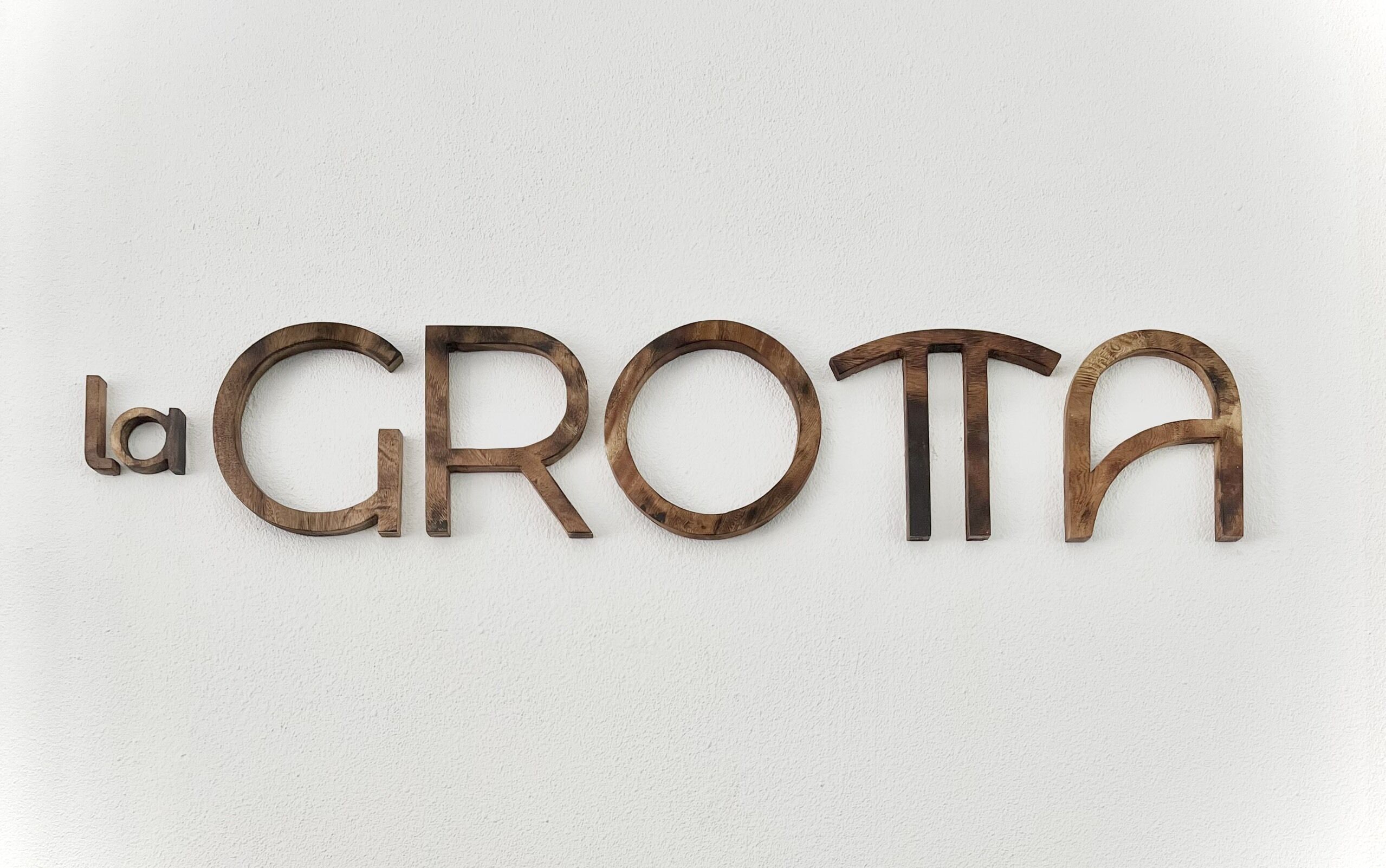 A wall with the text "la GROTA" in wooden letters.