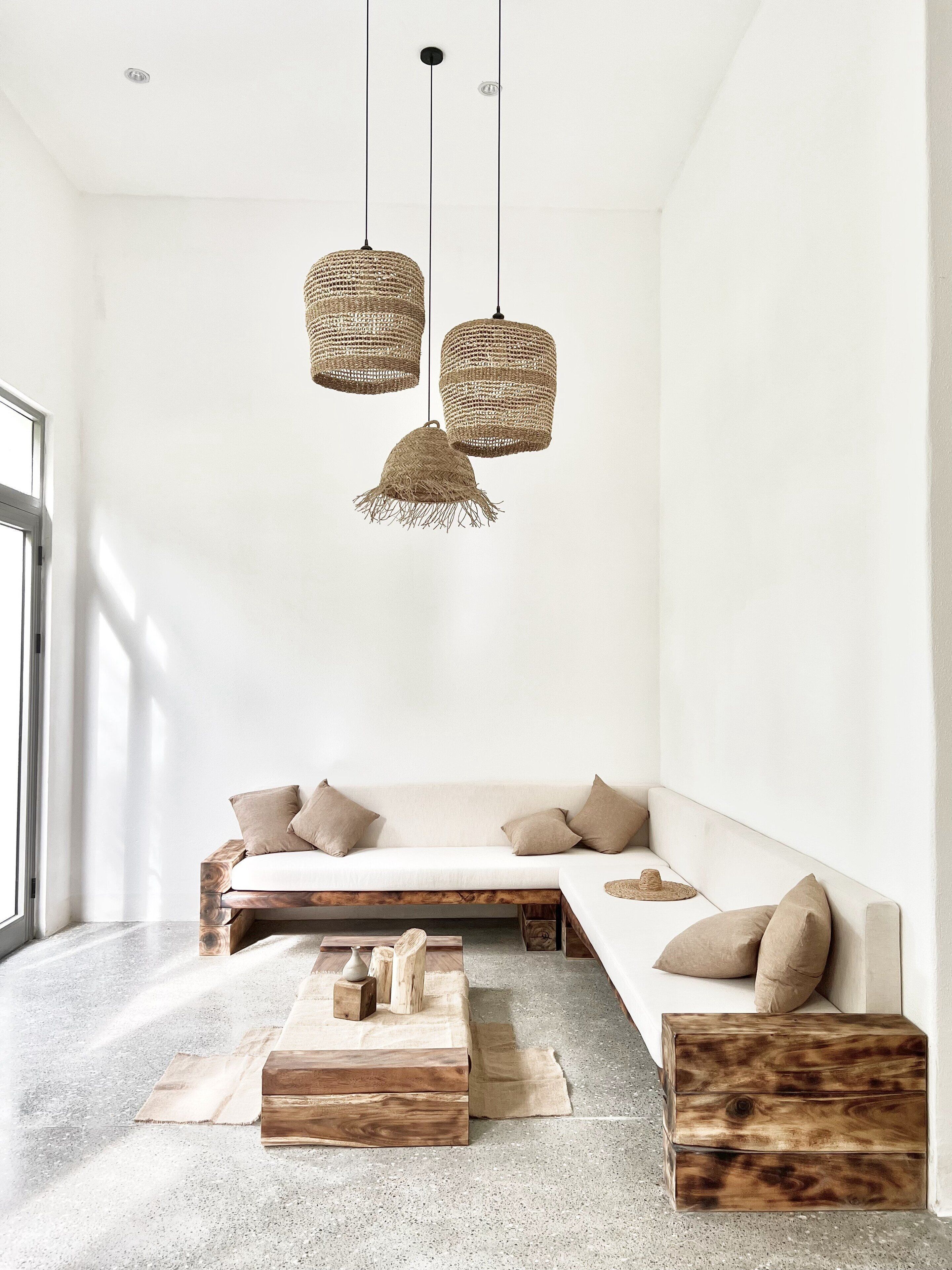 A modern living room with a minimalist design, featuring a sofa, wooden coffee table, and woven pendant lights.