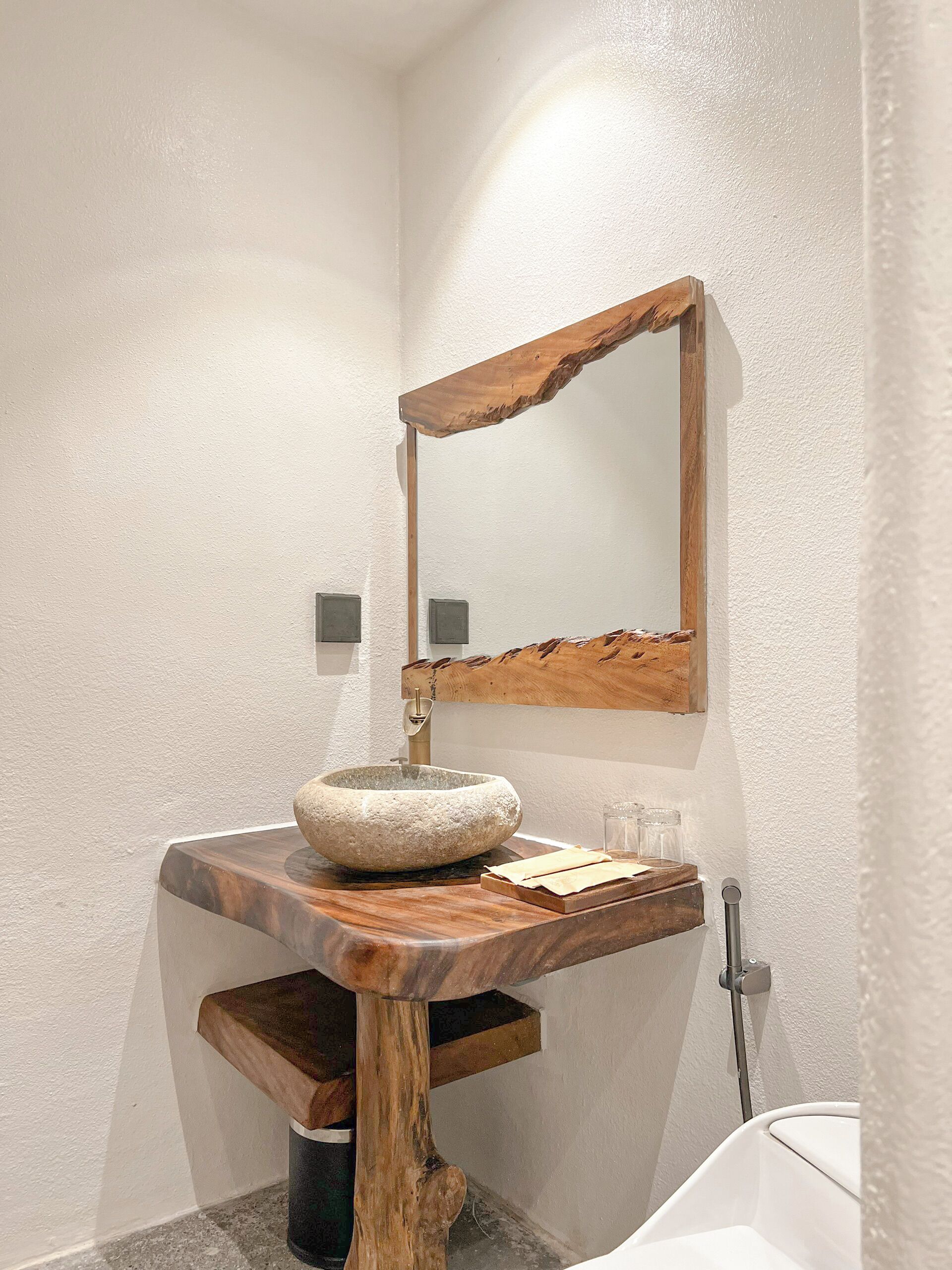 A bathroom with a stone sink, wooden countertop, and a large mirror.