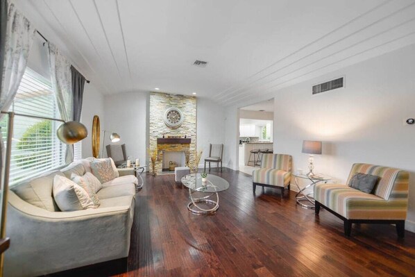 A spacious living room with a fireplace, a sofa, a striped armchair, and a coffee table. - Discover Serenity in this Tranquil Miami Home (Miami)
