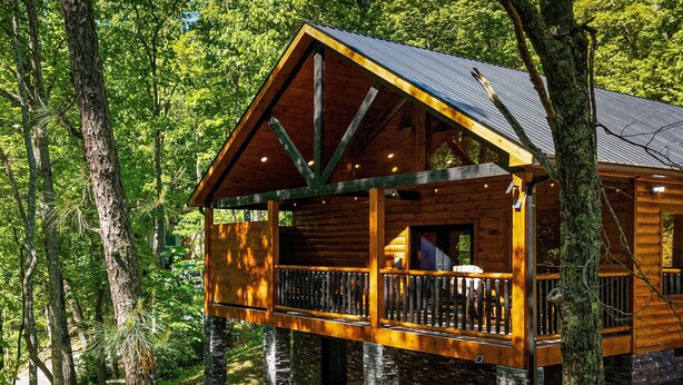 A wooden cabin with a balcony, surrounded by trees.