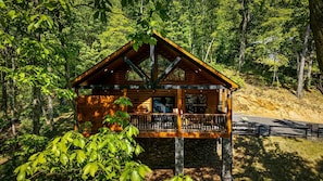Une cabane en bois dotée d’un balcon, entourée d’arbres.