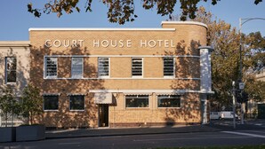Ein zweistöckiges Backsteingebäude mit einer gebogenen Ecke, mit der Aufschrift "Court House Hotel".