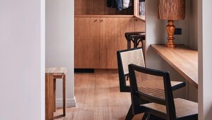 Eine moderne Küche mit Holzausstattung, einer Hängeleuchte und einem Essbereich mit zwei Stühlen und einem Tisch.