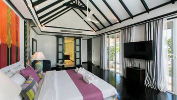 Quarto de hotel moderno com uma cama grande, uma televisão de tela plana e vista para o exterior.
