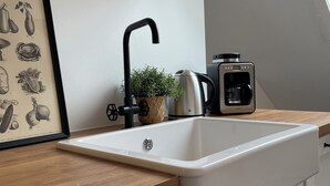 Eine Küche mit weißem Spülbecken, einem schwarzen Wasserhahn und einer Kaffeemaschine auf der Arbeitsfläche.