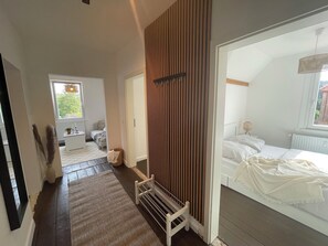 Ein Schlafzimmer mit Bett, Nachttisch, Fenster und Heizkörper.