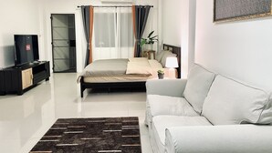 Una camera da letto moderna con un letto, una TV, un divano e una pianta in vaso.