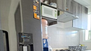 A modern kitchen with a stainless steel refrigerator, a microwave, and a built-in water dispenser.
