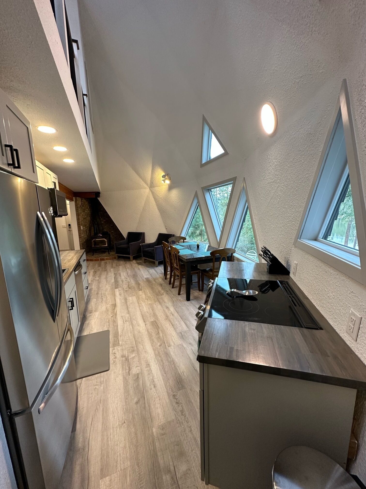 A modern kitchen with a central island, a dining area with a table and chairs, and a sloped ceiling with skylights.