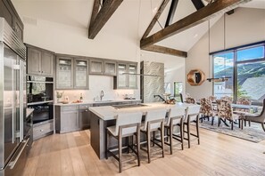A modern kitchen with a central island, built-in appliances, and a dining area with a view. - Shock Hill Overlook Gem | Gondola In/Out | VIEWS! (Breckenridge)