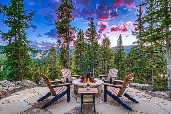 A fire pit surrounded by Adirondack chairs, set on a stone patio with a mountain view. - Shock Hill Overlook Gem | Gondola In/Out | VIEWS! (Breckenridge)