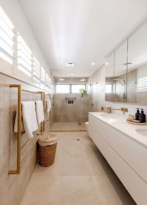 Un bagno moderno con doccia a ingresso diretto, uno specchio grande e un mobile lavabo con lavandino e ripiano.