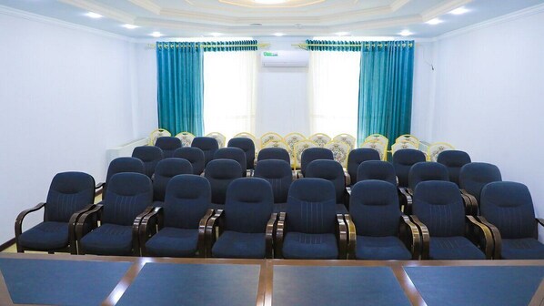 A conference room with rows of chairs, a podium, and curtains.