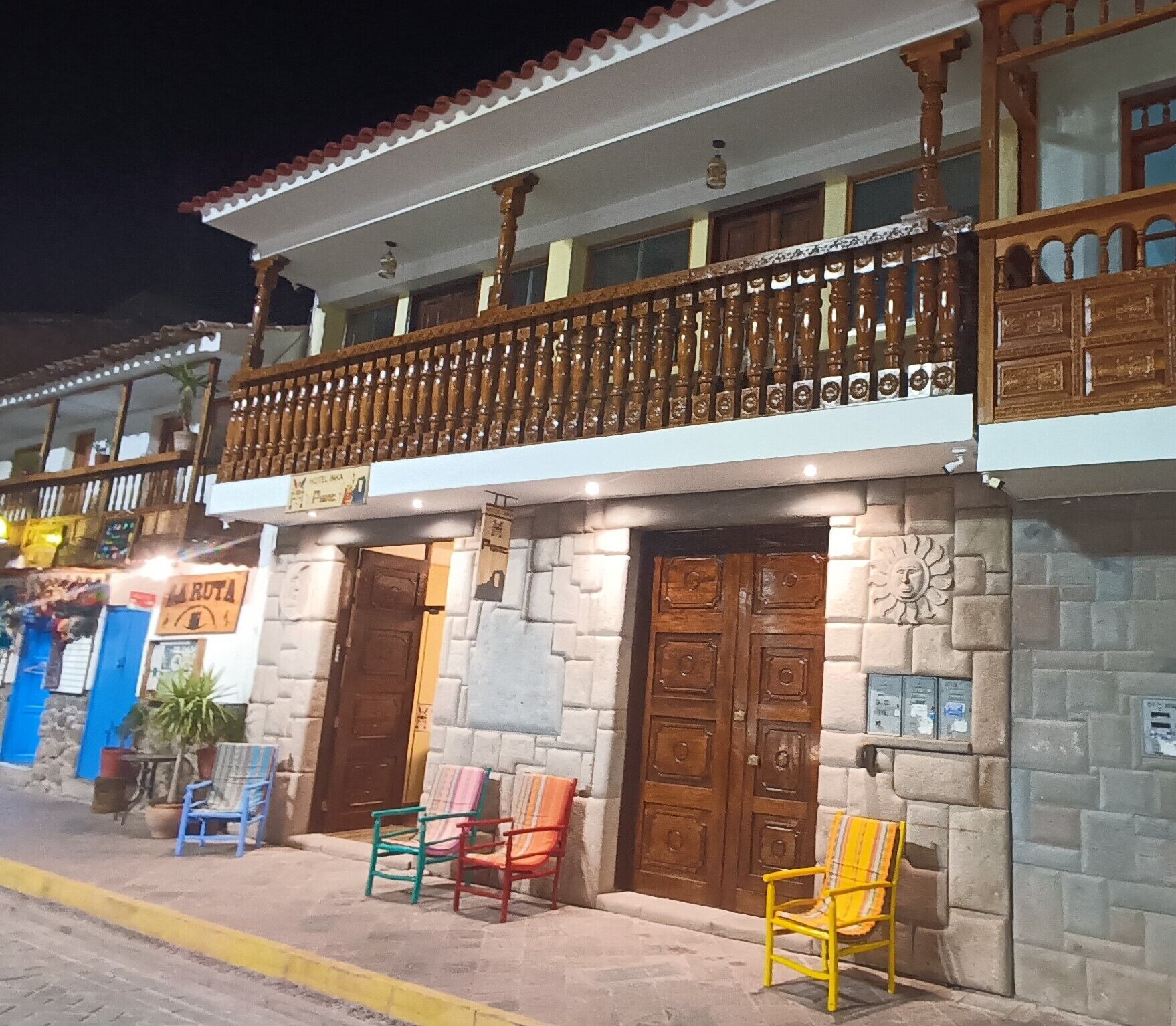 Un edificio de dos pisos con balcón, fachada de piedra y un letrero que dice 