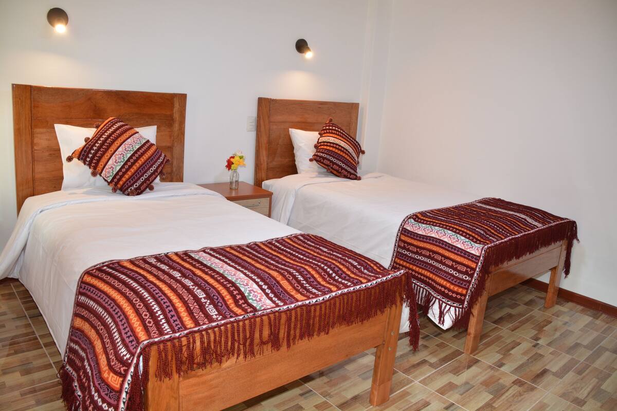 A double room with two beds, each with a wooden headboard and a patterned blanket.