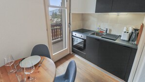 A compact kitchen with a dining area, including a table with chairs, a small oven, and a sink. - Elegant studio in the heart of Crans (Crans-Montana)
