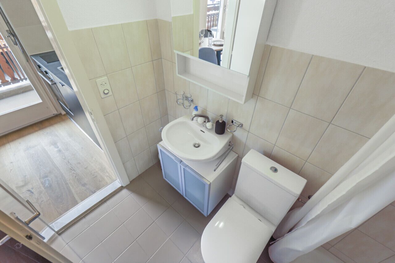 Un baño pequeño con inodoro, lavamanos y espejo.