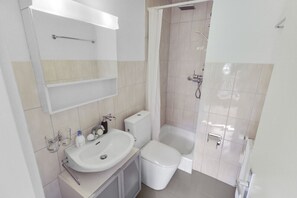 Un baño moderno con lavamanos, inodoro y zona de ducha.