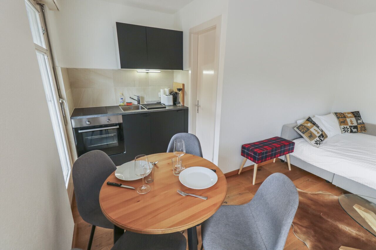 A compact living space with a kitchenette, a dining area, and a bed.