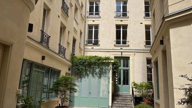 A narrow cobblestone courtyard with a green door labeled "LITURA" and potted plants. - Appartement Saint Antoine CityCosy (Paris)