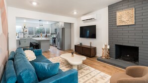 Una sala de estar moderna con un sofá azul, una mesa de centro blanca y una chimenea.
