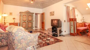 Ein Wohnzimmer mit einer Couch, einem Fernseher, einer Kommode und einem Essbereich mit einem Stuhl.