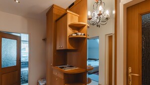Ein Zimmer mit einem Holzschrank, einer Kristallleuchtre, einem Bett und Blick durch eine Tür.