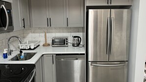 A modern kitchen with stainless steel appliances, including a refrigerator, oven, and microwave. - Modern Private Suite in a serene location 15 minutes away from the Airport. (Airdrie)