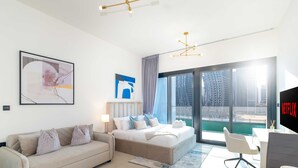 A modern hotel room with a bed, a sofa, a desk, and a large window with a view of the city. - LUX The Modern Binghatti Canal Suite (Dubai)