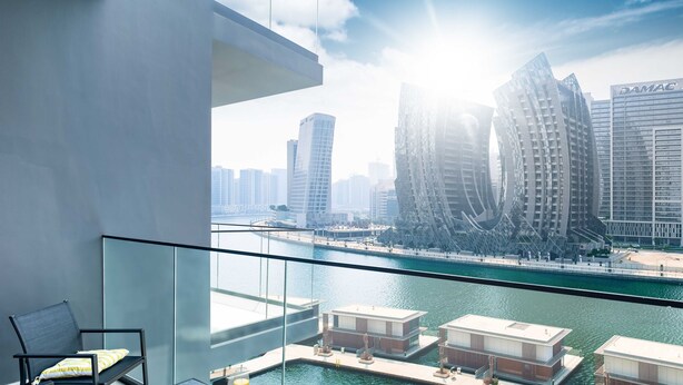 A modern hotel room with a balcony overlooking a marina and city skyline. - LUX The Modern Binghatti Canal Suite (Dubai)