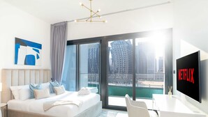 A modern hotel room with a large bed, a TV, and a view of a cityscape. - LUX The Modern Binghatti Canal Suite (Dubai)