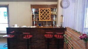 A bar area with a wooden counter, four red bar stools, and a wine rack behind the counter.