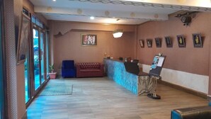 A reception area with a reception desk, a blue chair, a red sofa, and framed pictures on the wall.