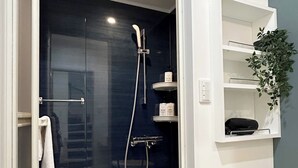 A modern bathroom with a glass-enclosed shower, white shelves with toiletries, and a wooden counter. - Deep Osaka! A Running Lamp 2 minutes from the station! Ideal location for sightseeing in Namba & USJ Osaka! Up to 6 people are allowed at the same price (大阪市)