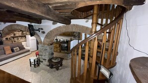Een landelijk interieur met een houten spiraaltrap, stenen muren en een keukenhoek.