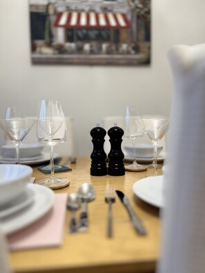 A dining table set for a meal, featuring wine glasses, a knife, fork, and spoon, along with plates and napkins.