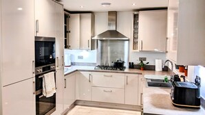 Una cocina moderna con electrodomésticos de acero inoxidable, estufa a gas y campana extractora.