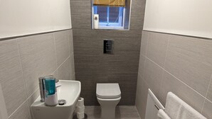 Un baño pequeño con lavamanos, inodoro y un ventanal.