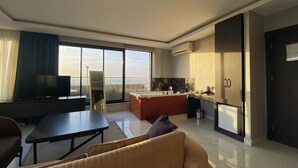 A modern living room with a sofa, a TV, a dining table, and a kitchen area with a refrigerator. - Elite Marmara Bosphorus Çamlıca (Istanbul)