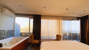 A hotel room with a large bed, a separate bathroom with a bathtub, two chairs, a table, and a balcony with a view. - Elite Marmara Bosphorus Çamlıca (Istanbul)