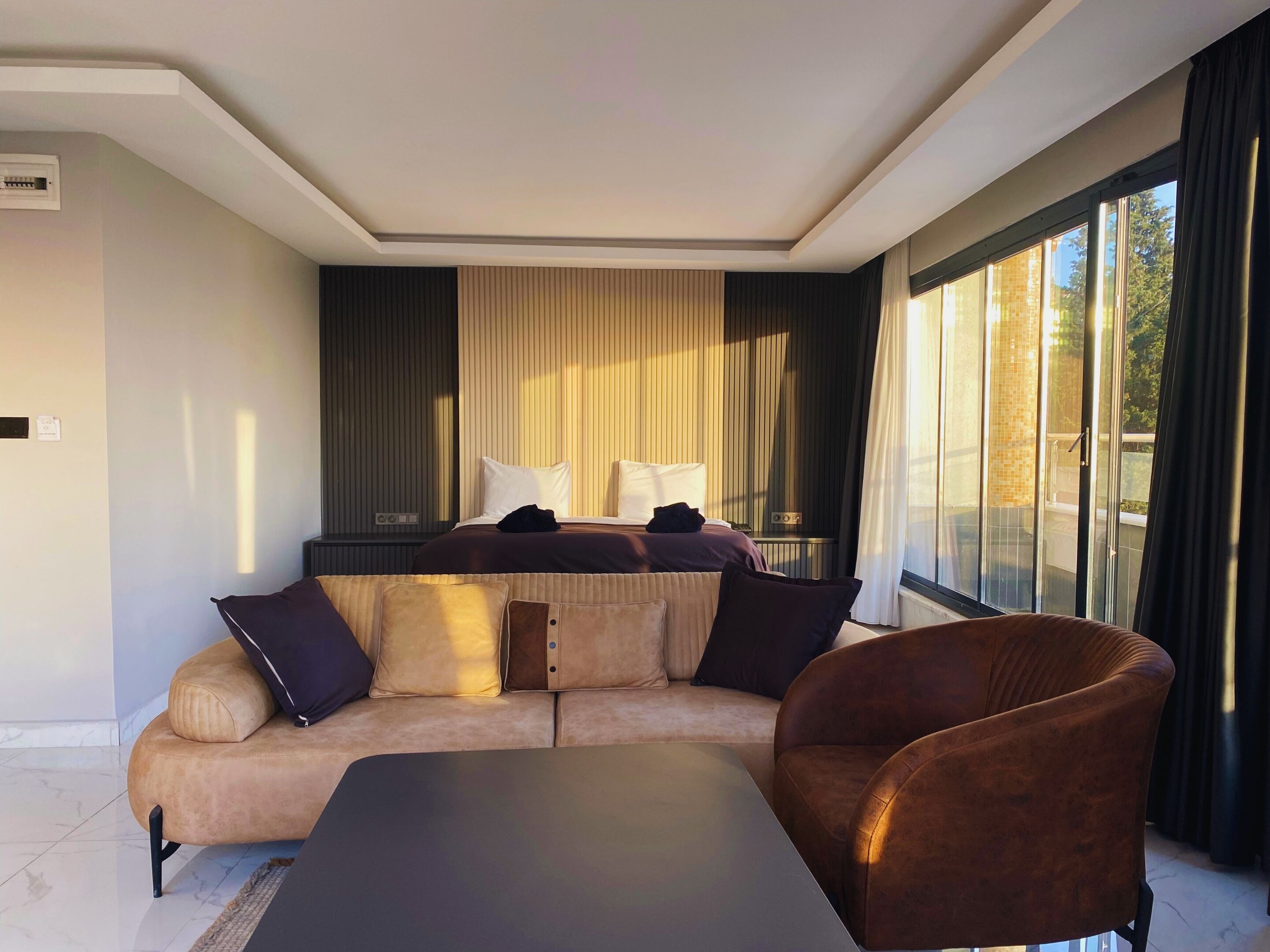 A modern living room with a sofa, a coffee table, and a large window with curtains.