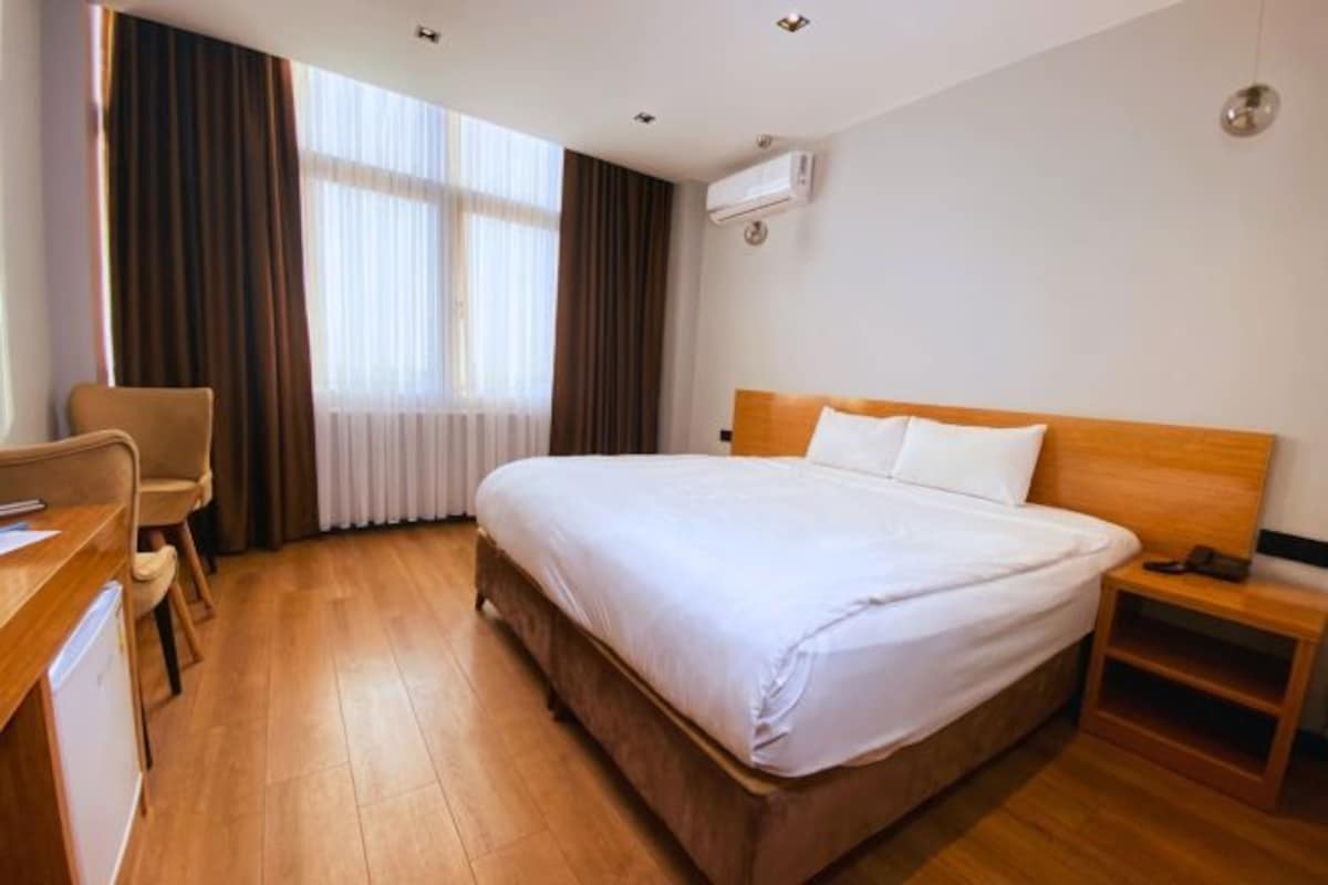Una habitación de hotel con una cama de madera, un escritorio y una silla.