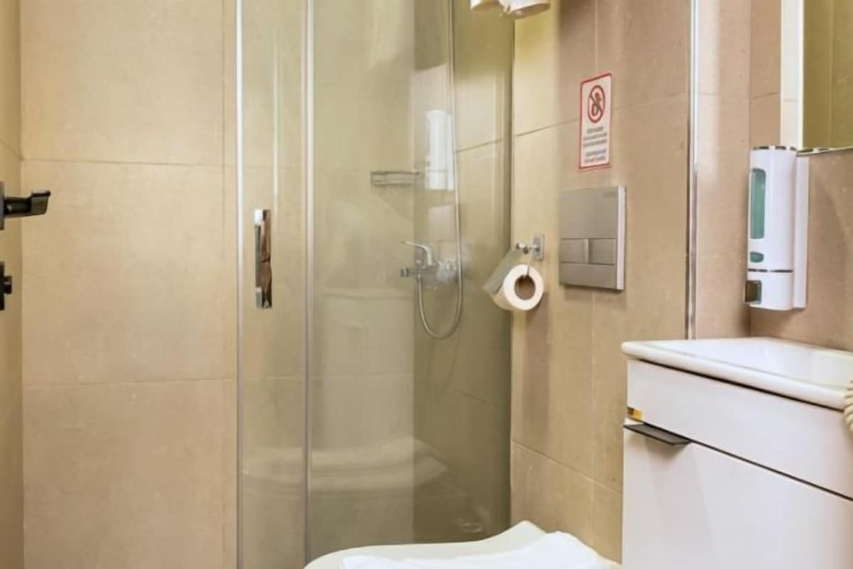 Un baño moderno con cabina de ducha de vidrio, inodoro y lavamanos.