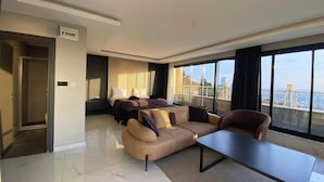 A modern hotel room with a large bed, a sofa, a coffee table, and a view of the city. - Elite Marmara Bosphorus Çamlıca (Istanbul)