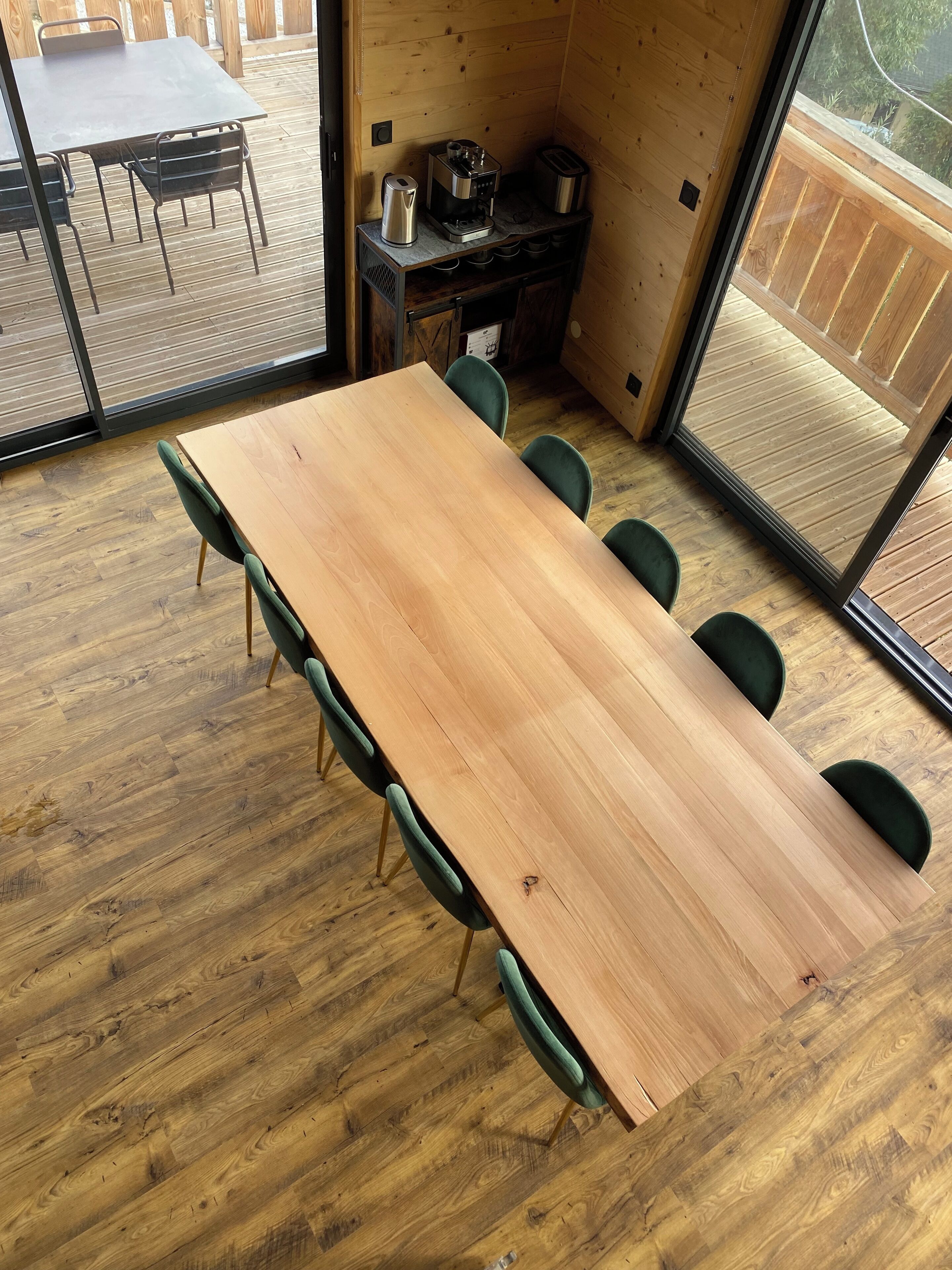 Une table à manger en bois, avec des chaises, une machine à café et un grille-pain, le tout posé sur une table en bois.