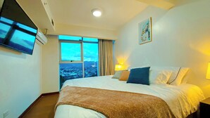 A hotel room with a large bed, a TV mounted on the wall, a window with a city view, and a painting on the wall. - Relaxing Apartment in the heart of San Jose (San José)