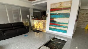 A reception area with a modern design, including a reception desk, a black sofa, and a large abstract painting on the wall. - Relaxing Apartment in the heart of San Jose (San José)
