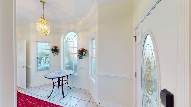 A hallway with a round table, two flower arrangements, a chandelier, and a stained glass window. - Four Bedroom, 3 Baths, Avian Forest, Scenic View (Pawleys Island)